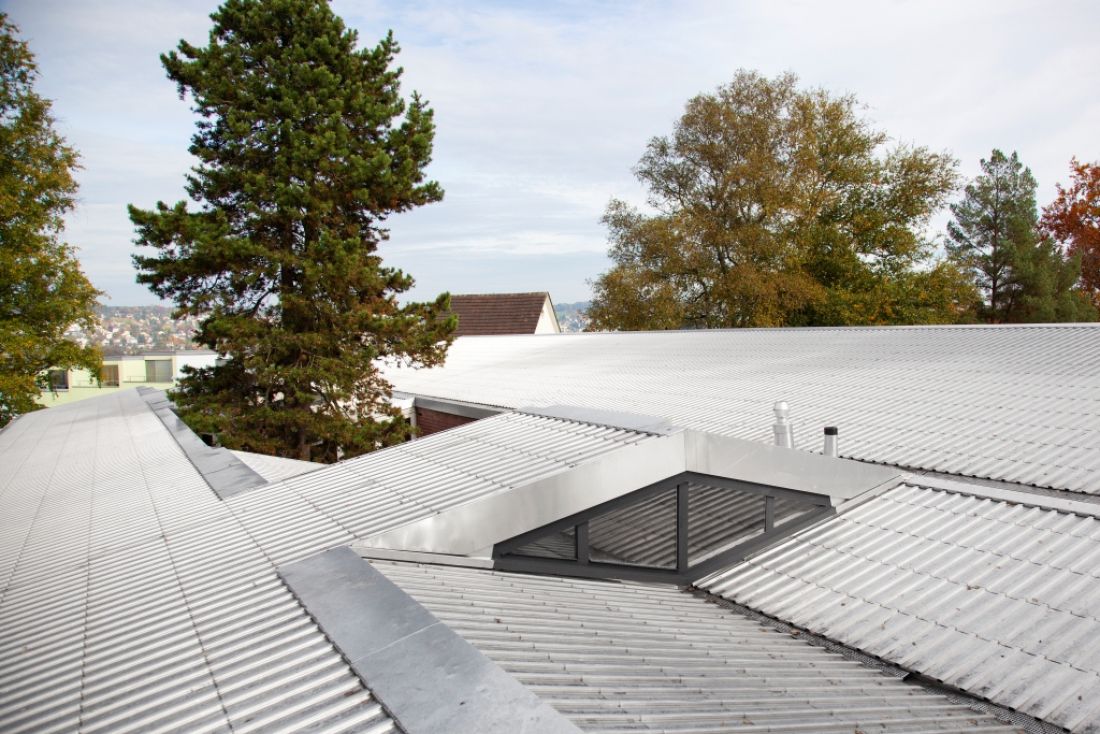 Flachdach mit Aluminium-Metalldach und Lichtkuppel, umgeben von Bäumen in der Schweiz, Aargau